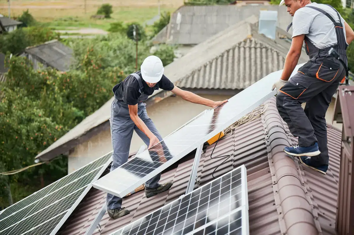 Solar installers mounting panels on a residential rooftop, with cost benchmark graphics implied